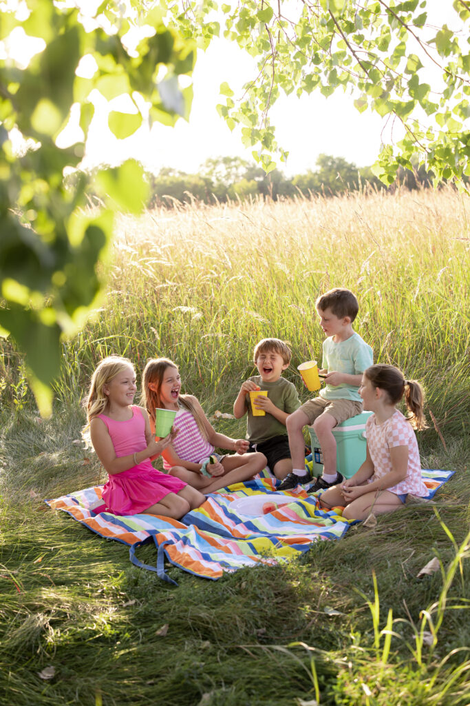 Kids sitting on a blanket with beautiful grass all around Familyfest Promo Photo